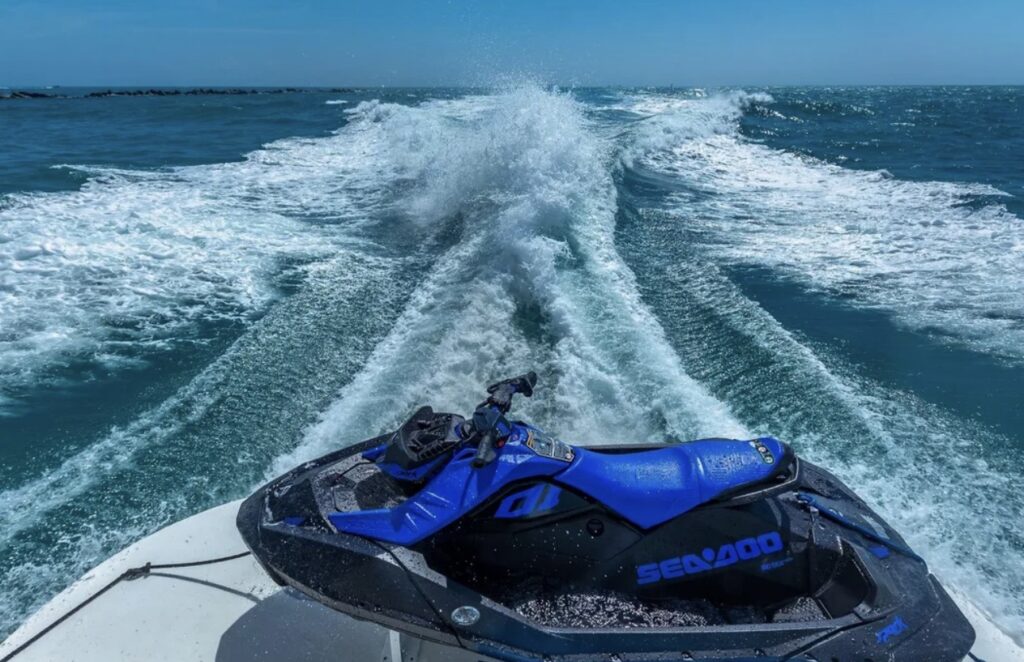 Jet ski speeding across ocean water leaving white trail behind