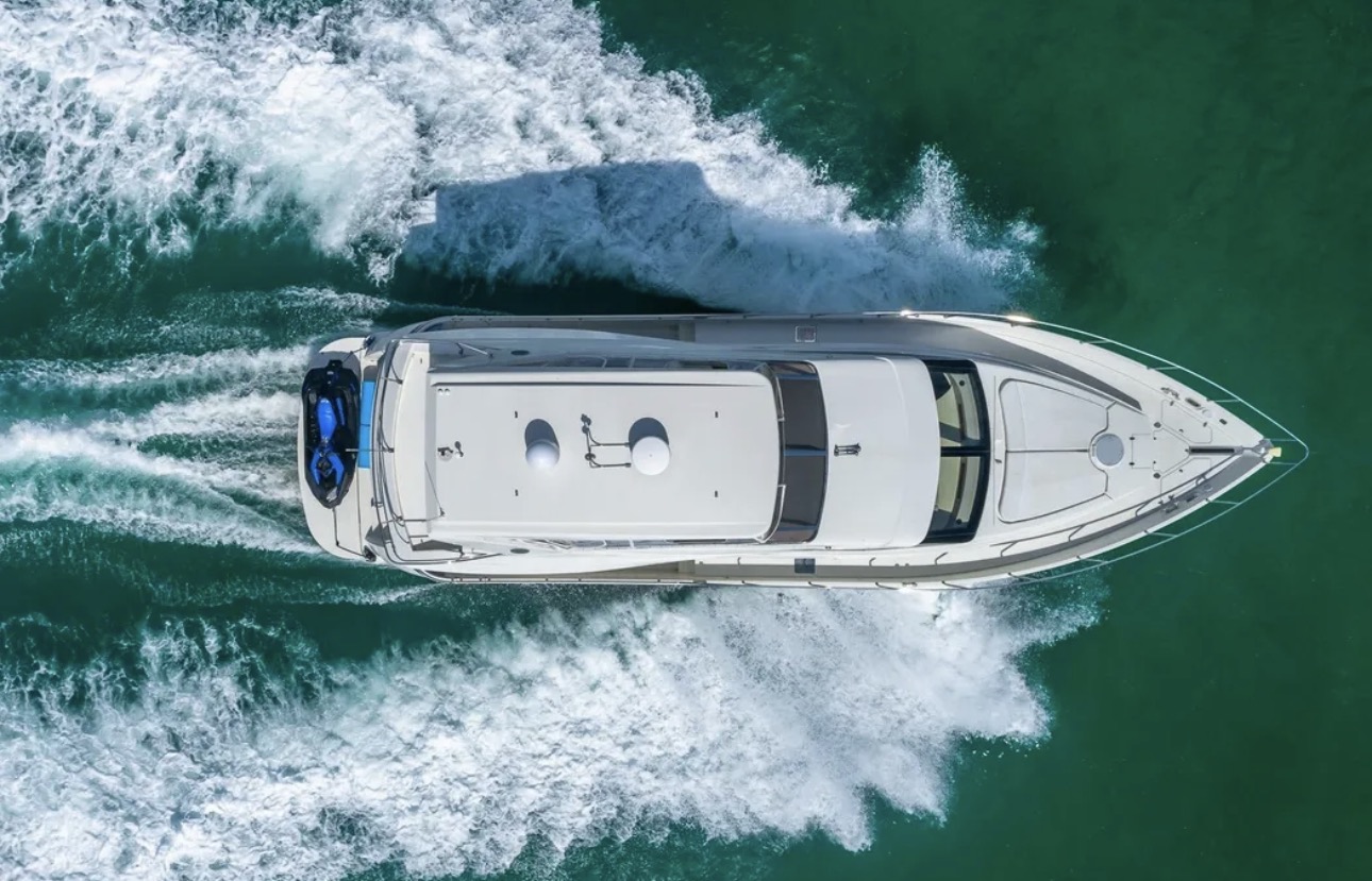 Aerial top view of yacht creating circular wake pattern in water