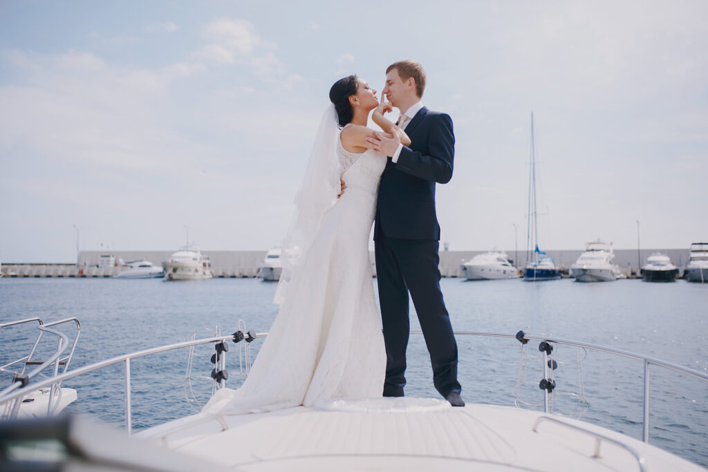 Elegant couple celebrating wedding on luxury yacht with ocean marina backdrop