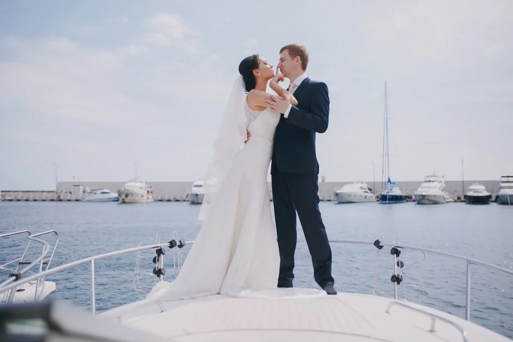 Romantic wedding couple kissing on yacht deck with marina and luxury boats background