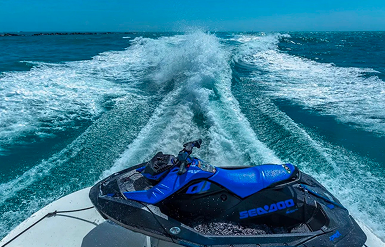 Jet ski speeding across water leaving foamy trail behind