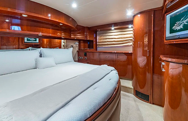 Yacht bedroom interior with large bed and glossy wooden cabinetry