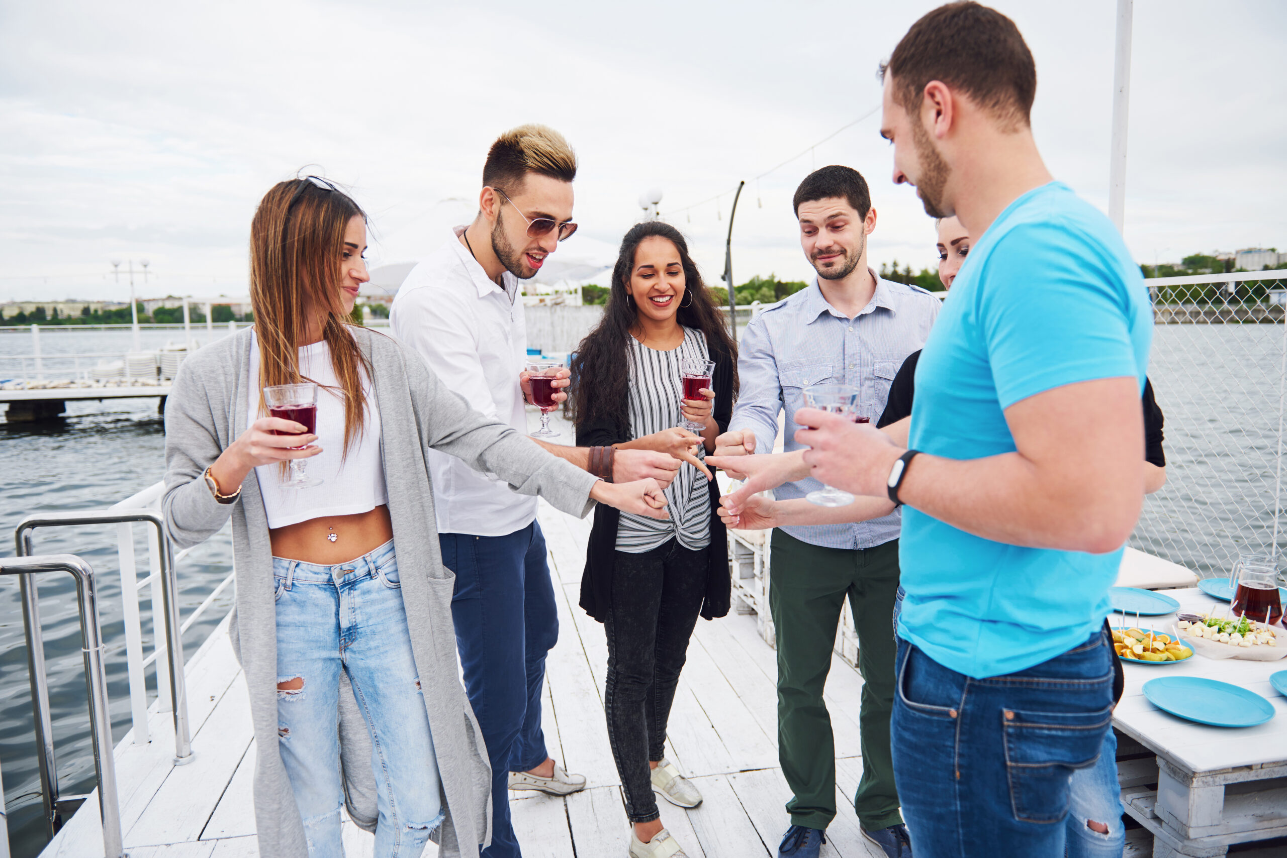 Group of young adults socializing and laughing outdoors in sunny setting