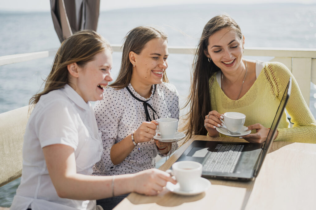 Friends enjoying coffee together indoors with laptop and casual conversation